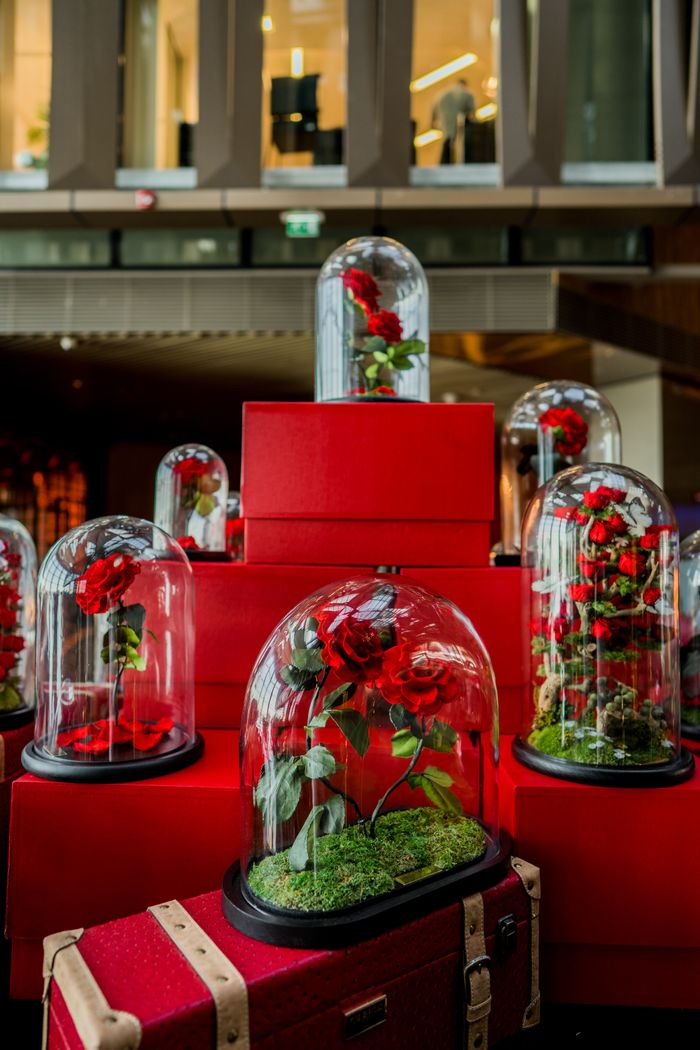 Elegant glass-encased roses on red boxes in a Dubai hotel lobby setting.